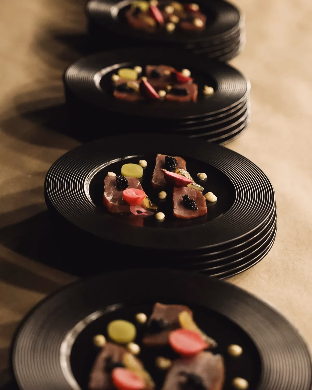 Przystawki z tuńczyka z kawiorem na czarnych talerzach, catering premium Warszawa